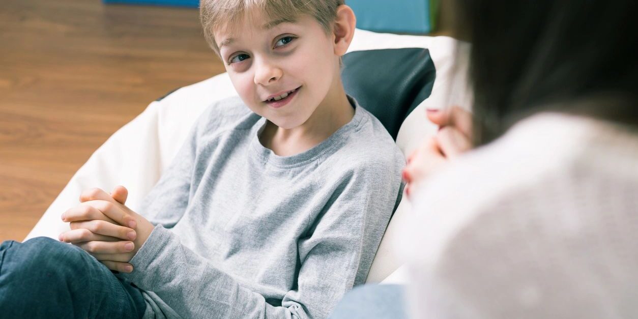 A boy sitting in front of another person.